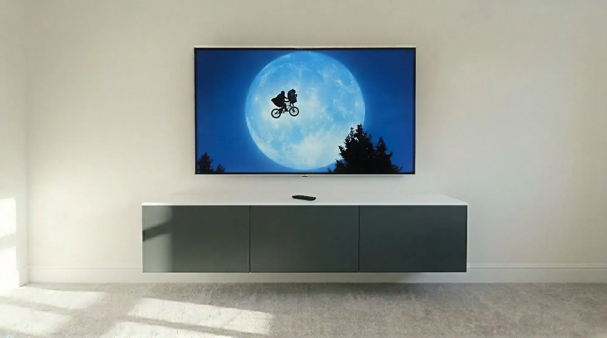 Large TV wall mounted above a floating grey media unit with no visible cables, Colchester