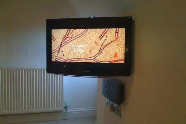 TV mounted on uneven stone cottage wall with custom packing for level finish