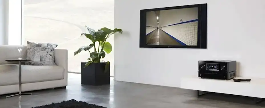 Professional home cinema installation with wall-mounted TV and AV receiver in a modern living room