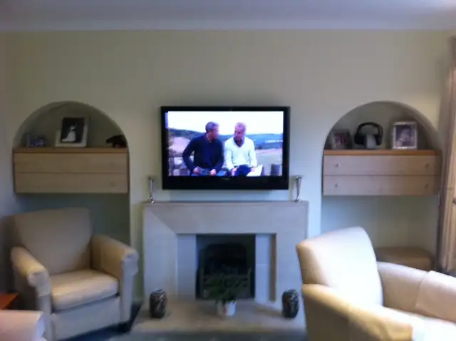 TV wall mounted above fireplace with surround sound speakers